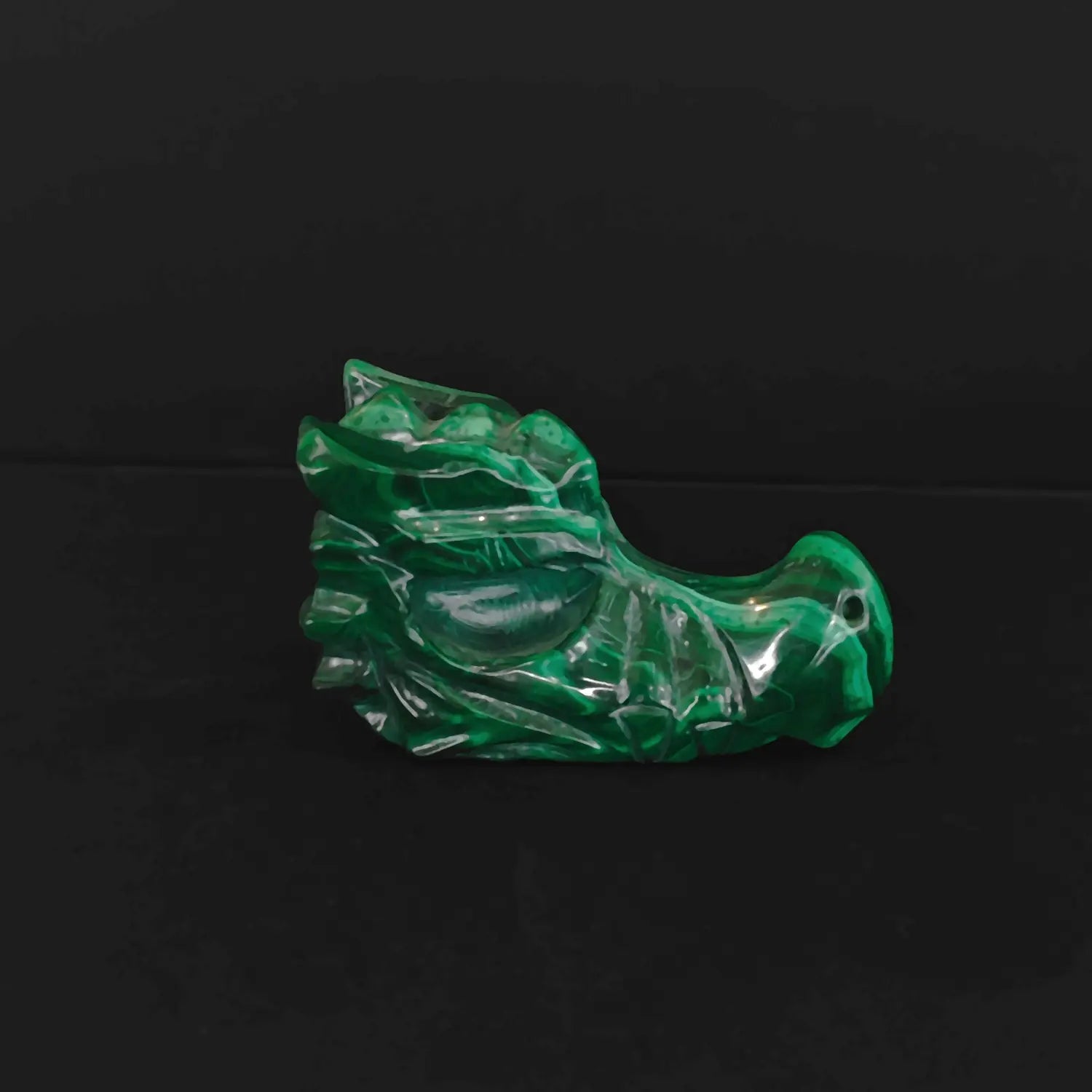 Natural malachite dragon carving shown from image_2bdc58.jpg with deep green banded patterns on black background