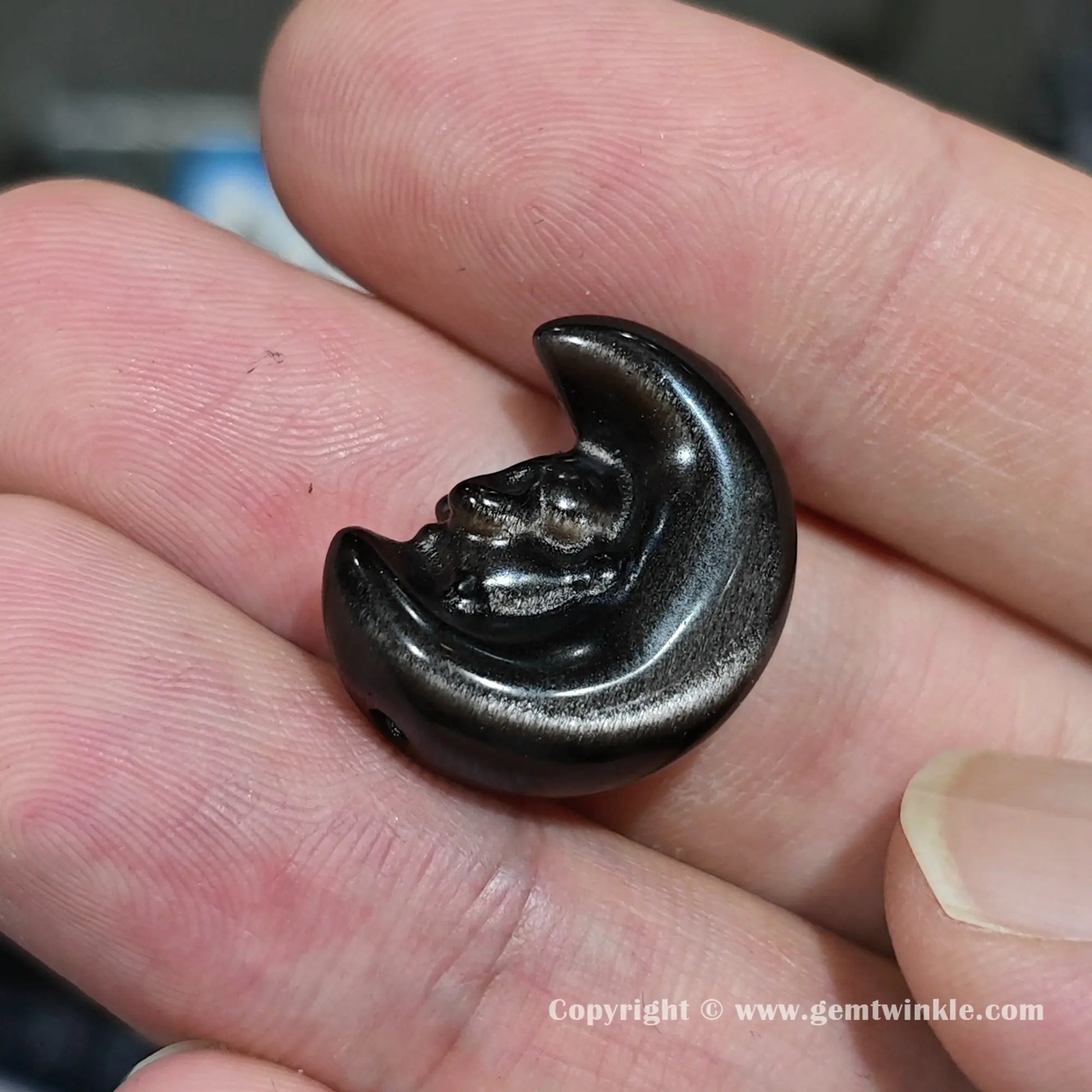 Side angle of natural obsidian starry bunny moon charm bead showing drilled hole positioning and size on fingers