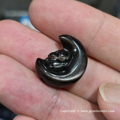 Side angle of natural obsidian starry bunny moon charm bead showing drilled hole positioning and size on fingers
