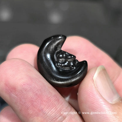 Side angle of natural obsidian starry bunny moon charm bead showing drilled hole positioning and size on fingers