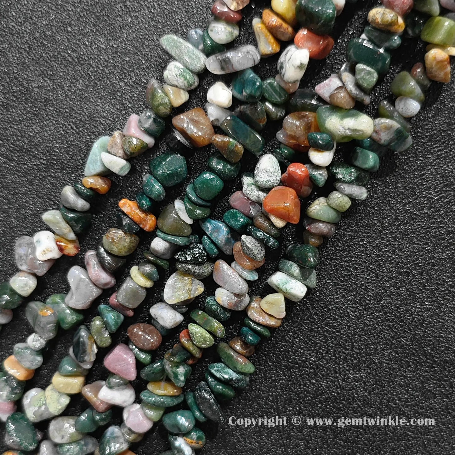 Angled view of tumbled ocean jasper freeform chip gemstone strands