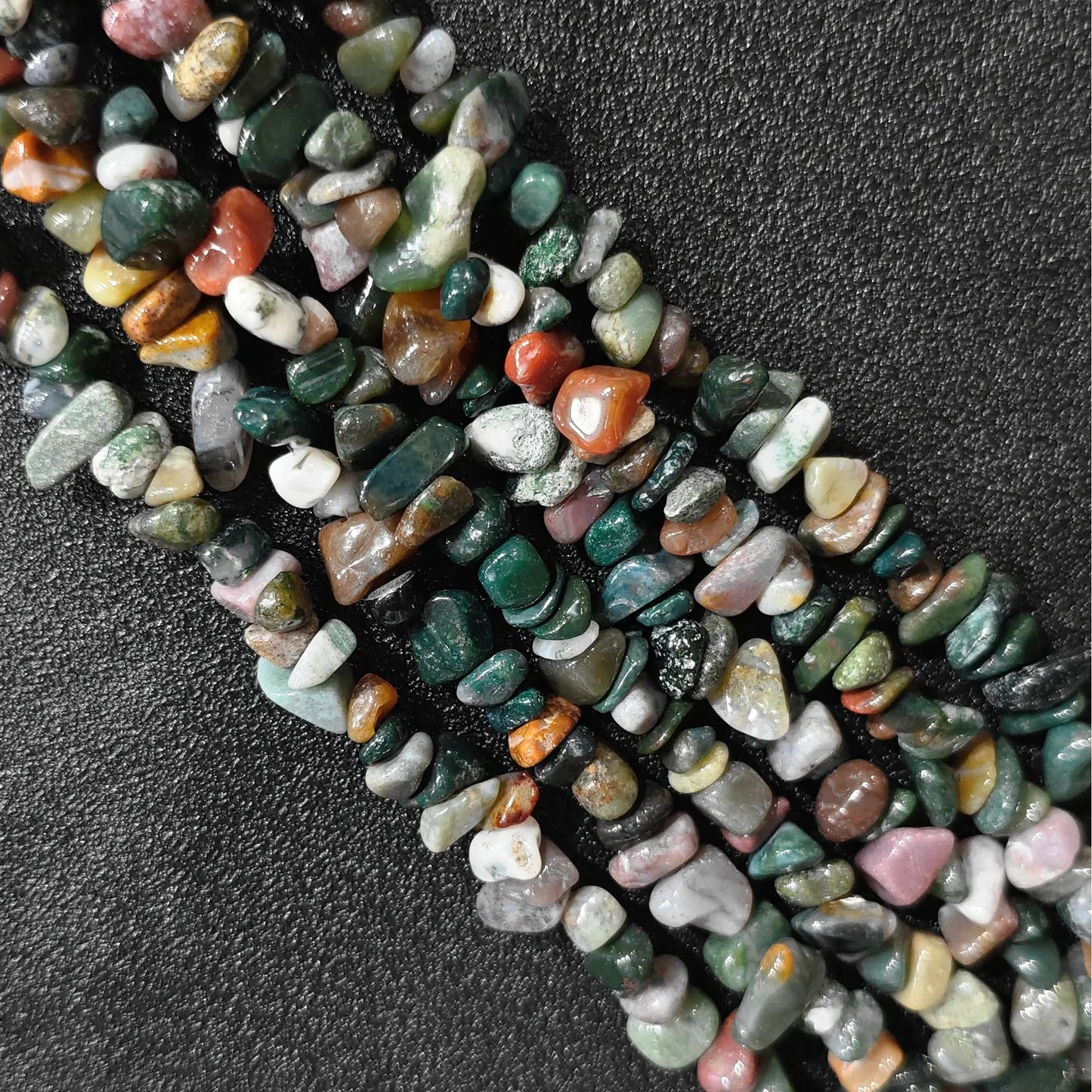 Macro closeup of natural ocean jasper irregular chip beads displaying earthy pattern variations
