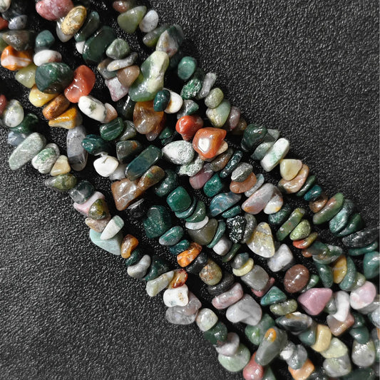 Macro closeup of natural ocean jasper irregular chip beads displaying earthy pattern variations