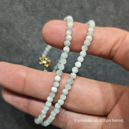 Detailed macro view of 3mm micro faceted green angelite beads showing opaque pale green mineral texture