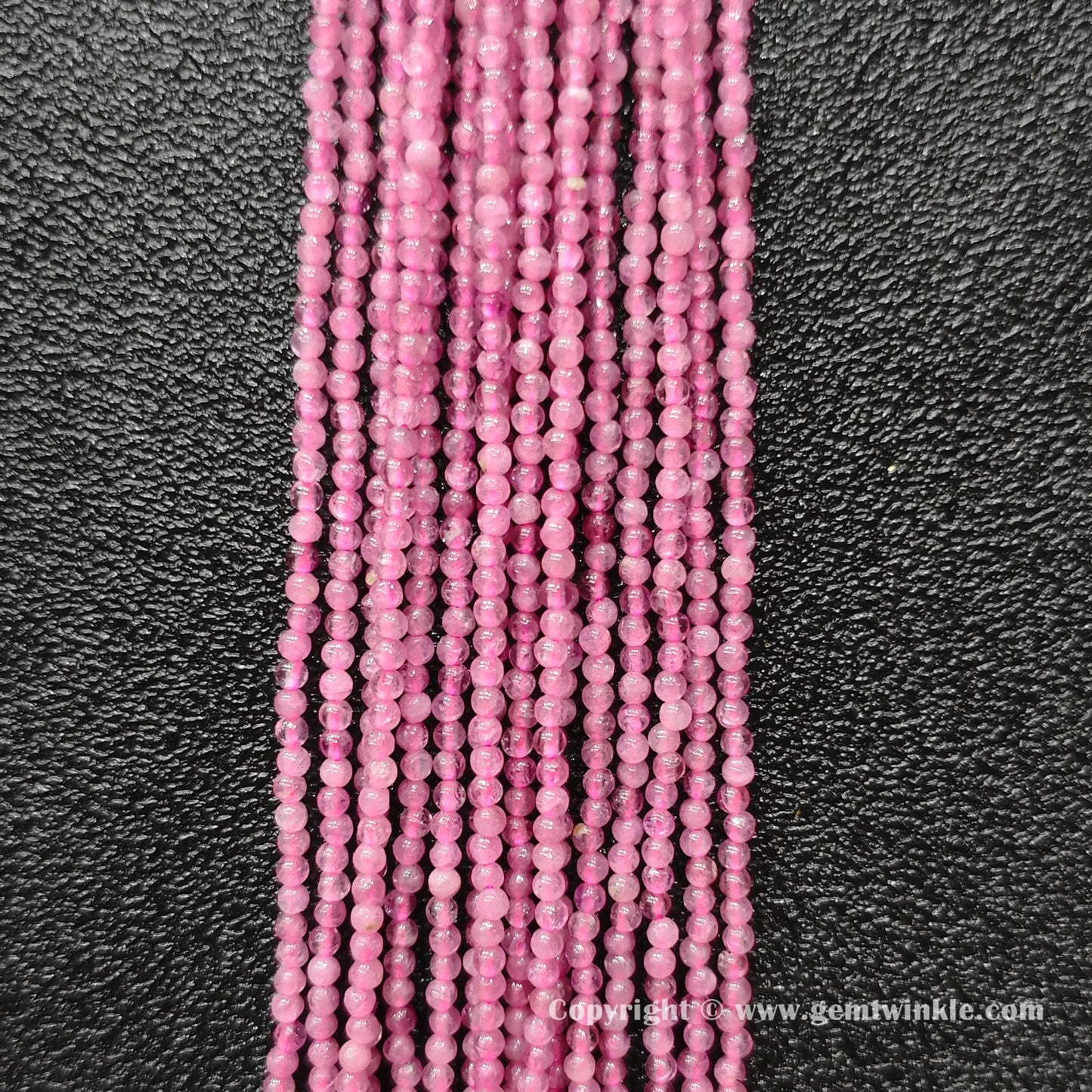 Vertical view of natural pink tourmaline micro round bead strands displaying vivid pink color