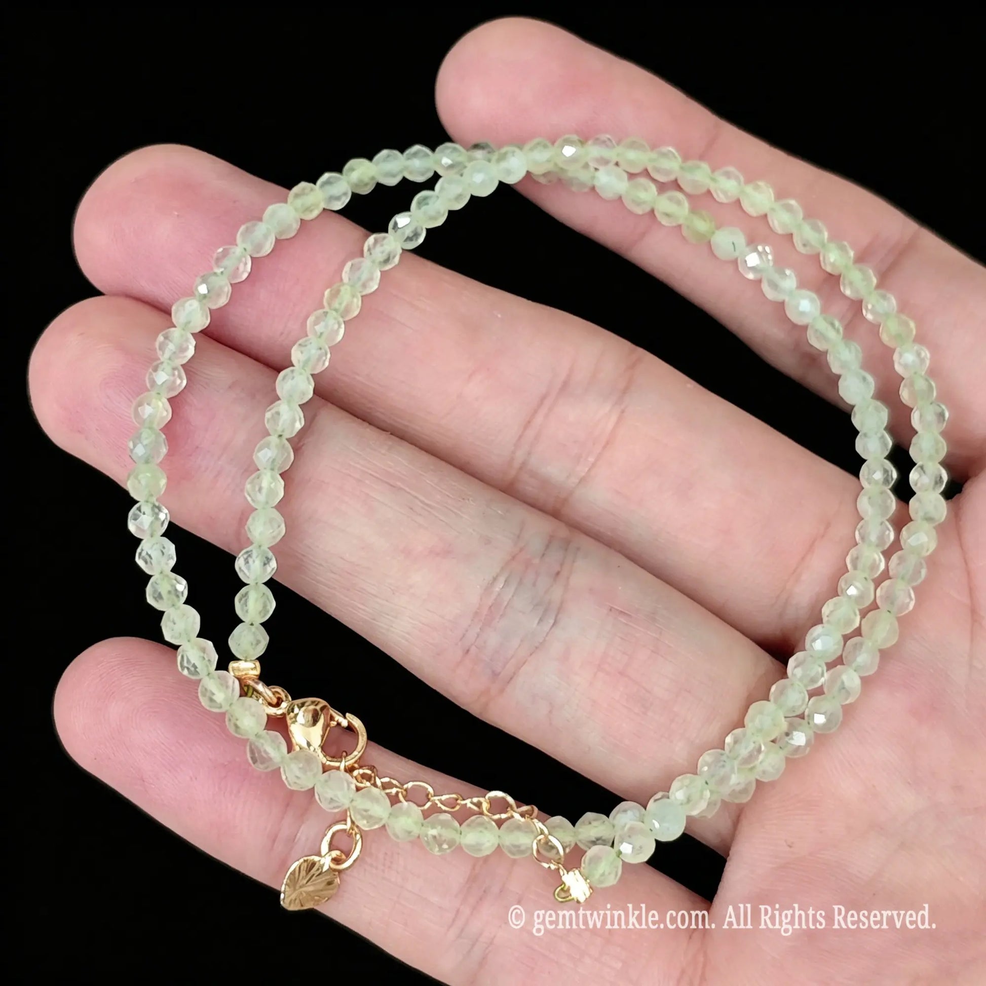 single strand prehnite gemstone choker resting on open palm showing pastel green glow