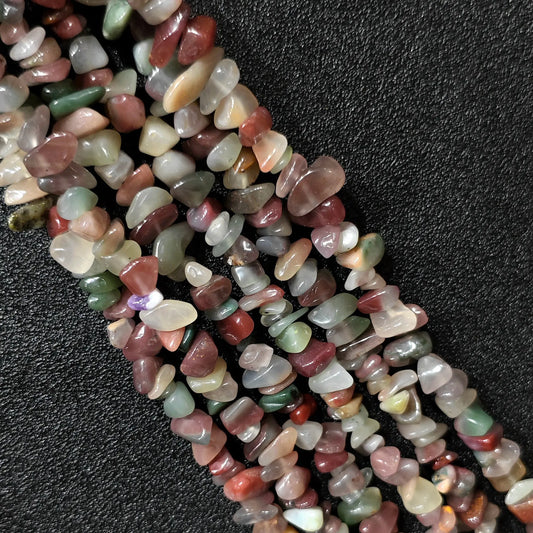 Macro closeup of natural purple and green agate irregular chip beads showing soft lavender and olive tones