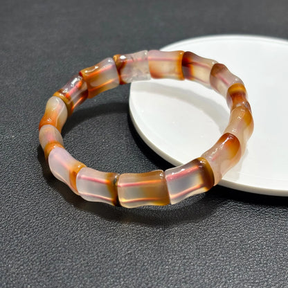 Single Natural Red Agate Bangle Bracelet resting on a white plate, showing the bamboo bead shape and warm red-brown hues.