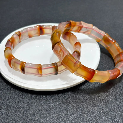 Close-up of two Natural Red Agate Bangle Bracelets on a white plate, emphasizing the texture and natural variations in the agate.
