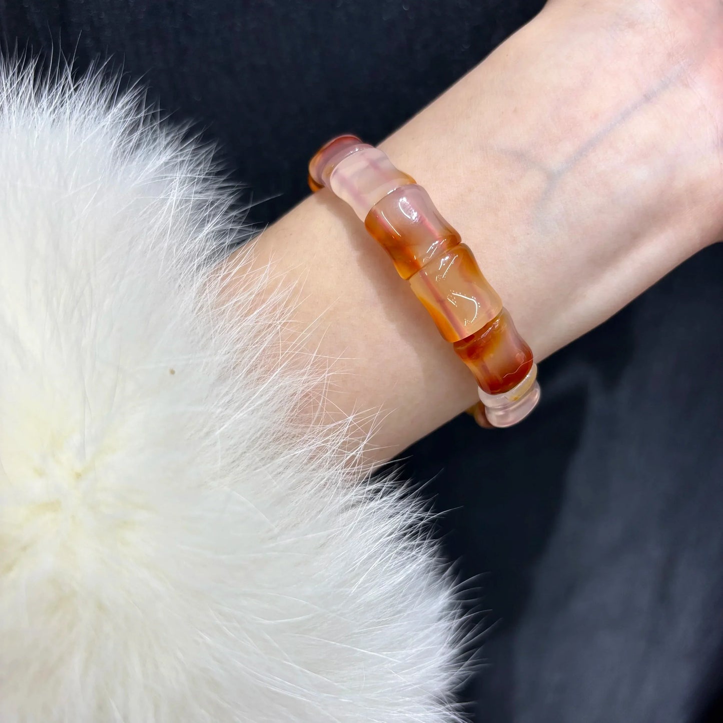 Model wearing a Natural Red Agate Bangle Bracelet on wrist, styled with a white fur accessory, demonstrating the fit and look when worn.