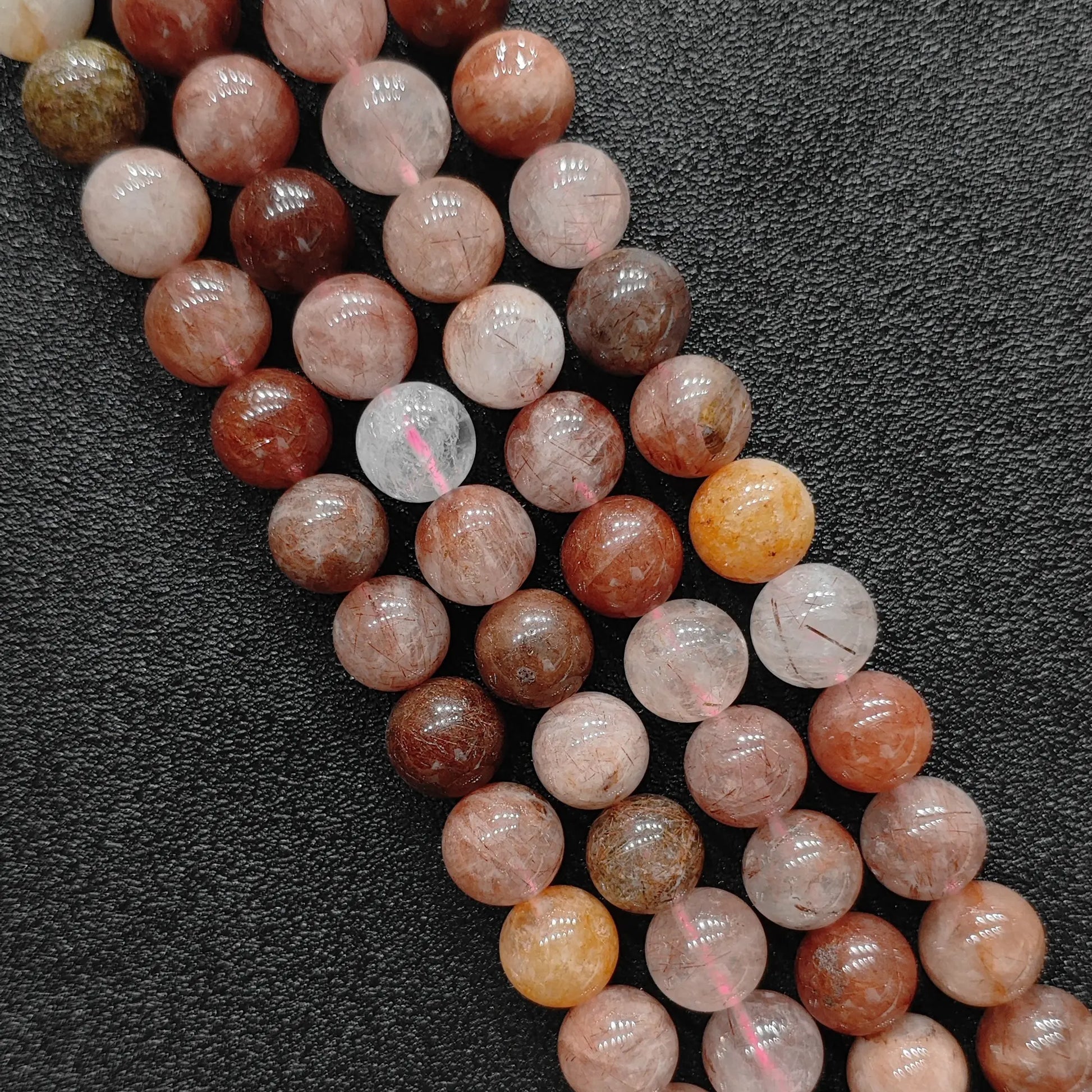 Close up view of natural red rutilated quartz strands showing genuine copper needle inclusions and phantom layers on a dark textured background