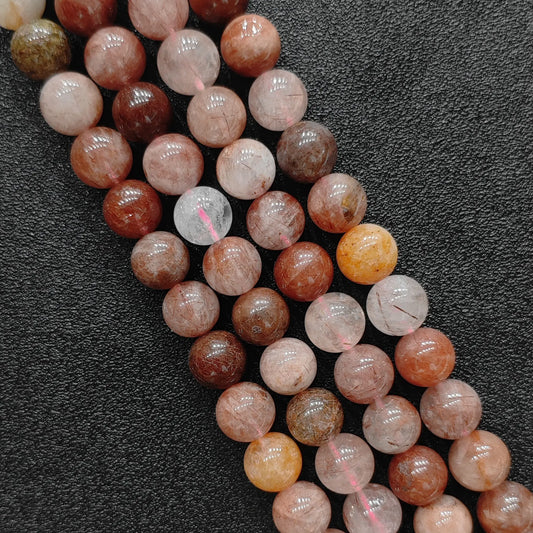 Close up view of natural red rutilated quartz strands showing genuine copper needle inclusions and phantom layers on a dark textured background
