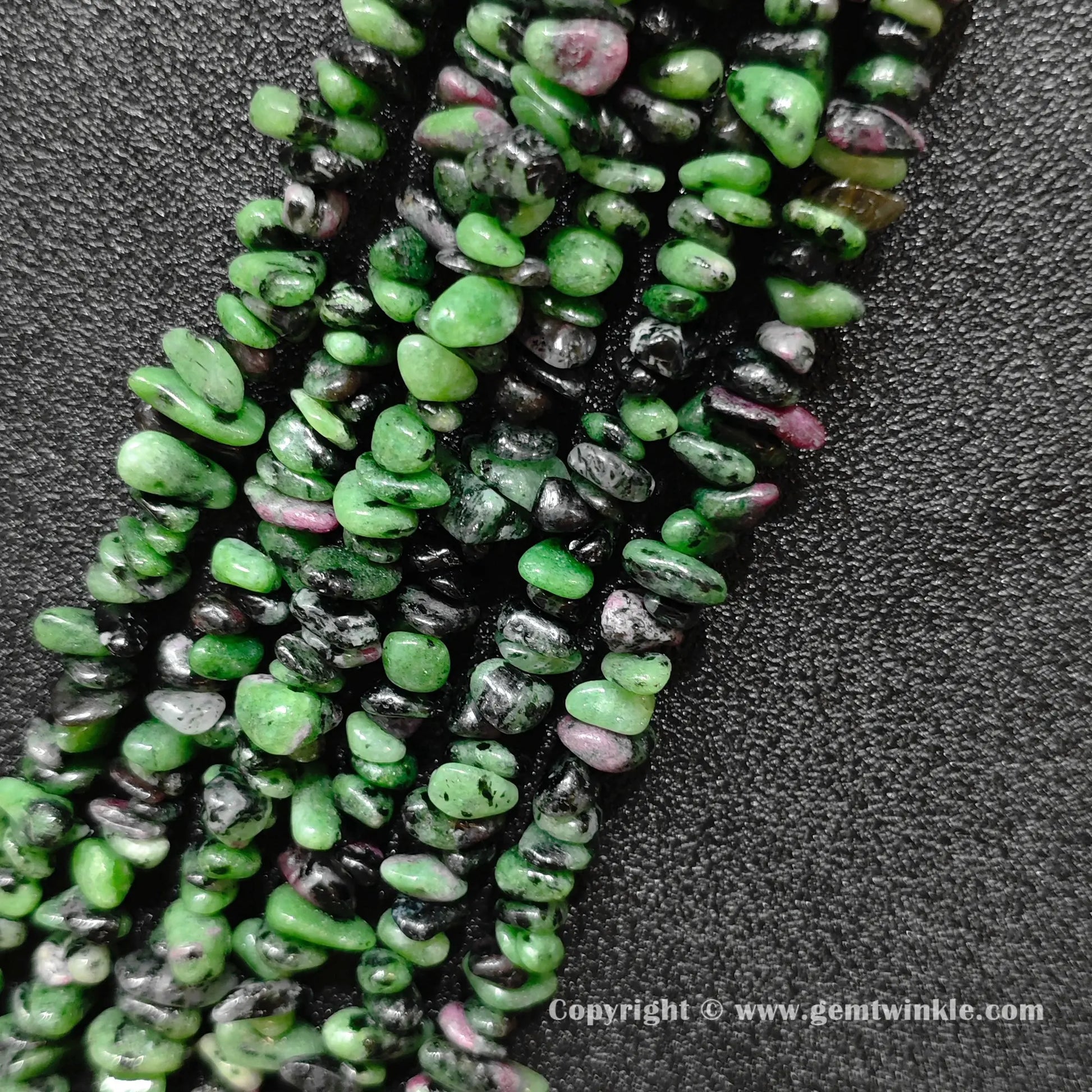 Angled view of tumbled ruby zoisite freeform chip gemstone strands