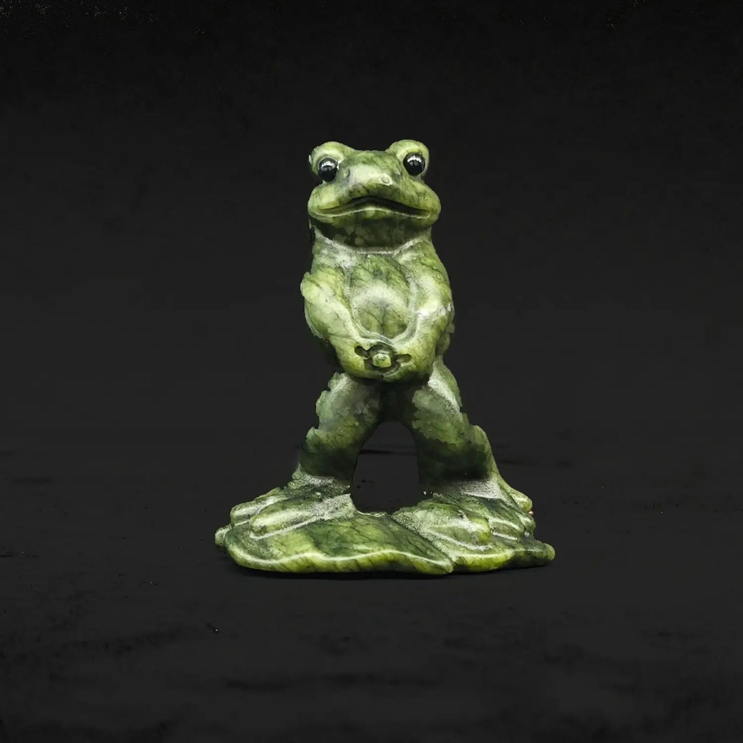 Front view of a natural serpentine peeing frog statue displaying a funny wide eyed toad standing upright in a hilarious pose