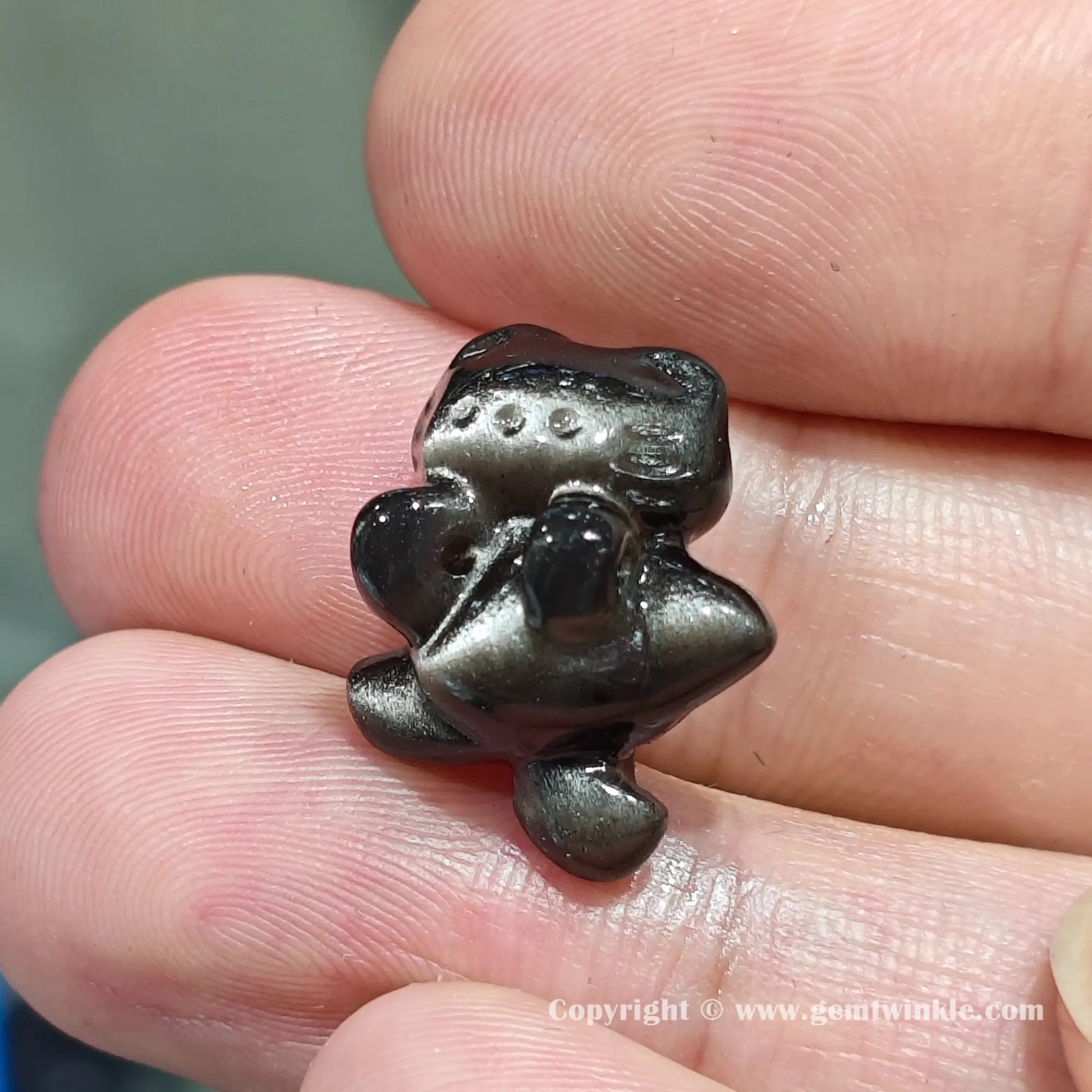Close up details of silver obsidian kissing cat focal charm bead displaying bright metallic silver shimmer on finger