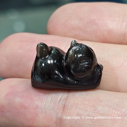 Close up details of silver obsidian stretching cat focal charm bead displaying bright metallic silver shimmer on finger