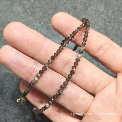 Detailed macro view of 3mm micro faceted Silver Sheen Obsidian beads showing dark volcanic glass with silver sheen