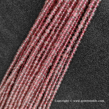 Angled view of translucent strawberry quartz gemstone strands in small sizes