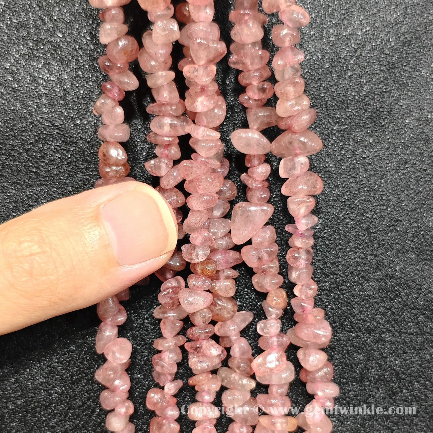 Hand holding 75cm continuous strand of natural strawberry quartz irregular chip beads
