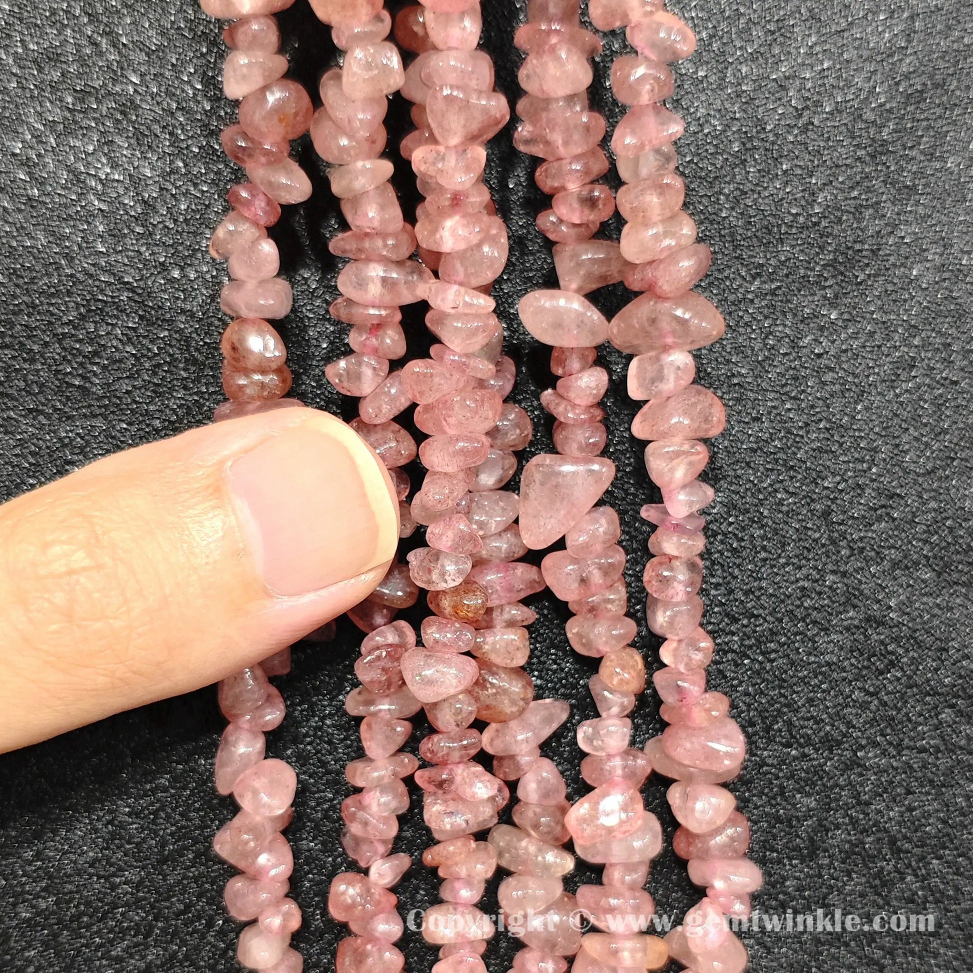 Hand holding 75cm continuous strand of natural strawberry quartz irregular chip beads