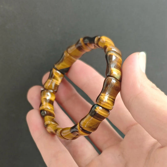 Natural Tiger Eye gemstone bamboo carved tube bead bracelet held on hand displaying chatoyant golden brown luster