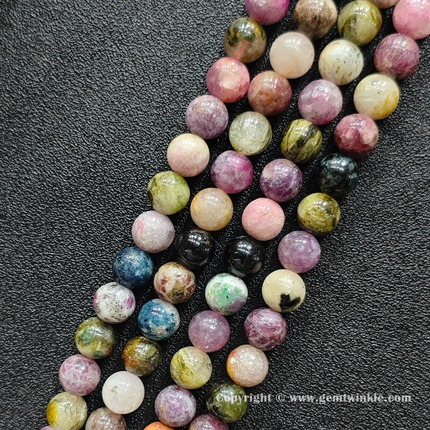 Close up detail of natural Grade C tourmaline round beads with organic mineral texture