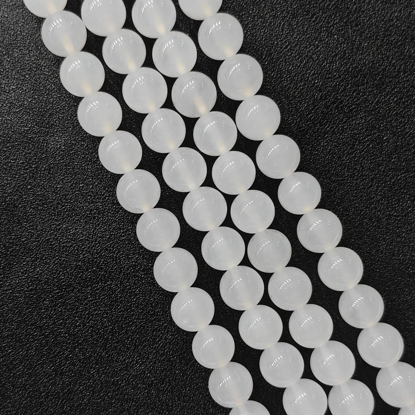 Natural milky white agate smooth round beads bulk strands showing soft glossy finish on dark background