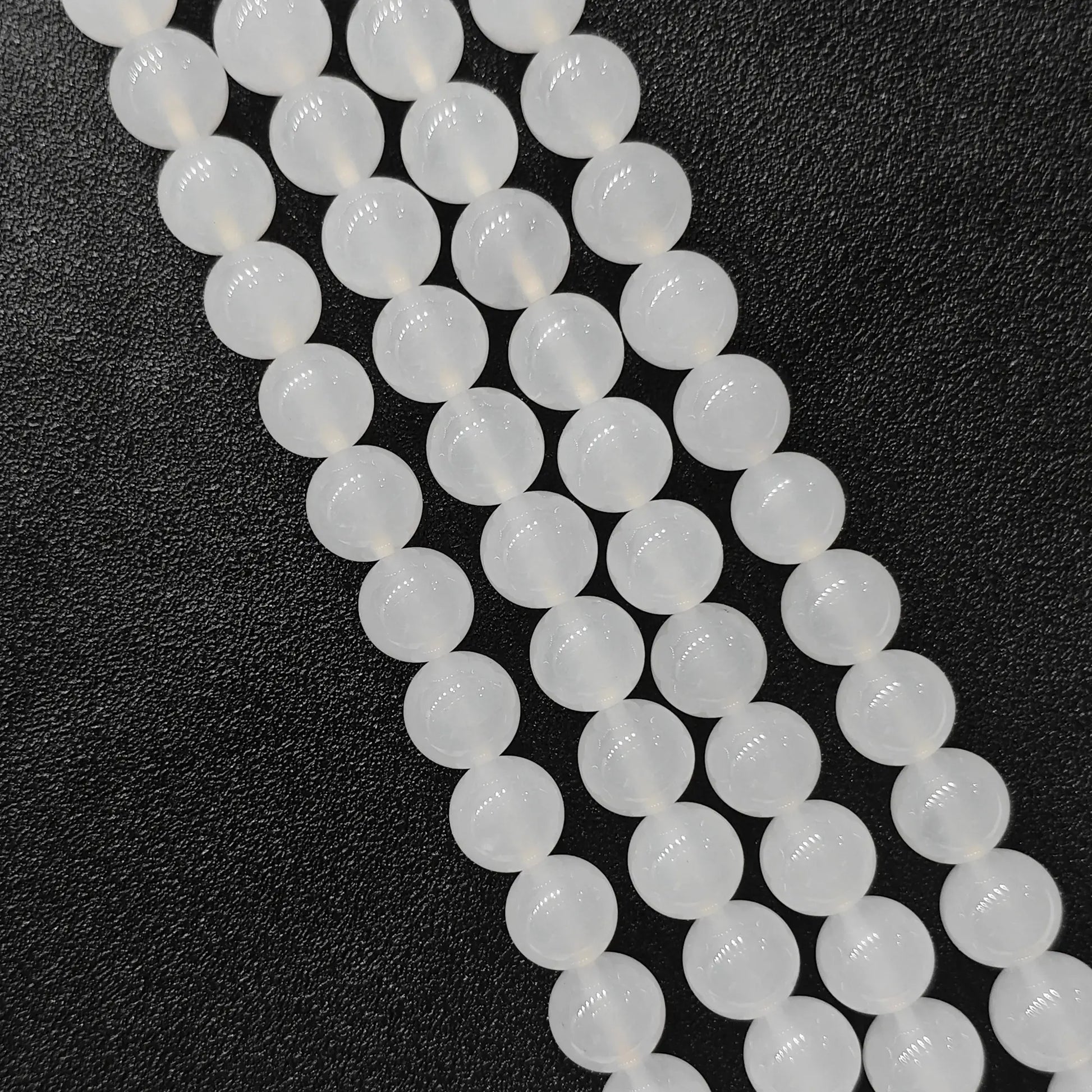 Natural milky white agate smooth round beads bulk strands showing soft glossy finish on dark background