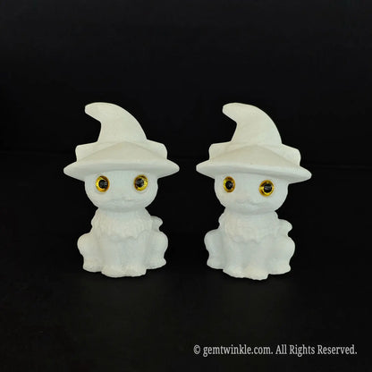 Two 6cm natural white marble cute witch cat figurines with pointed hats and big inlaid amber eyes sitting side by side on a black background