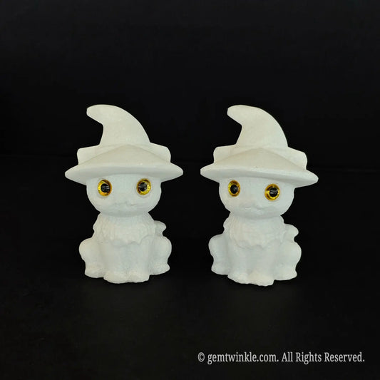 Two 6cm natural white marble cute witch cat figurines with pointed hats and big inlaid amber eyes sitting side by side on a black background