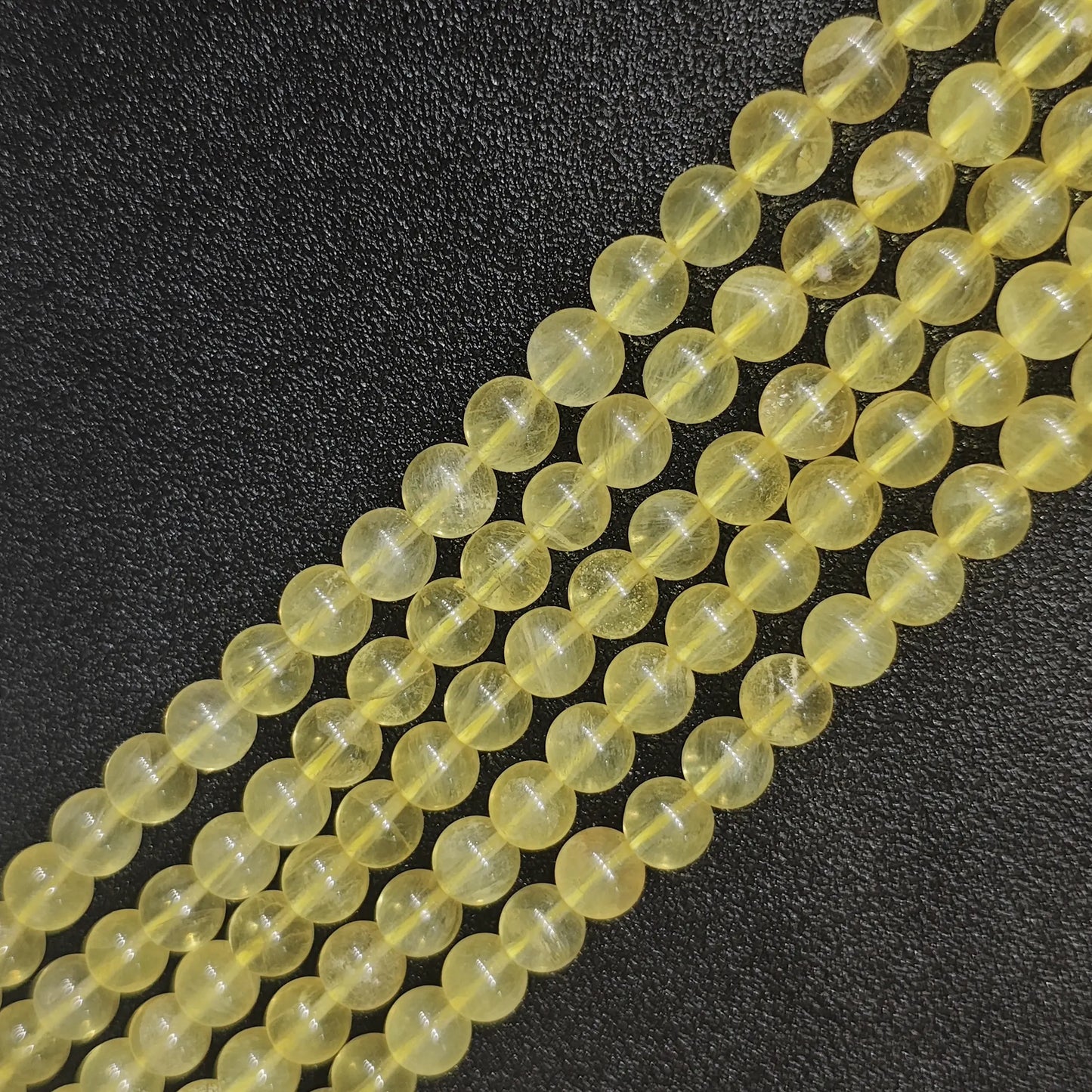 Grade AB natural yellow fluorite round loose beads strands with golden translucent colors and subtle internal cracks on a dark background