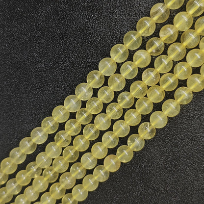Grade AB natural yellow fluorite round loose beads strands with golden translucent colors and subtle internal cracks on a dark background