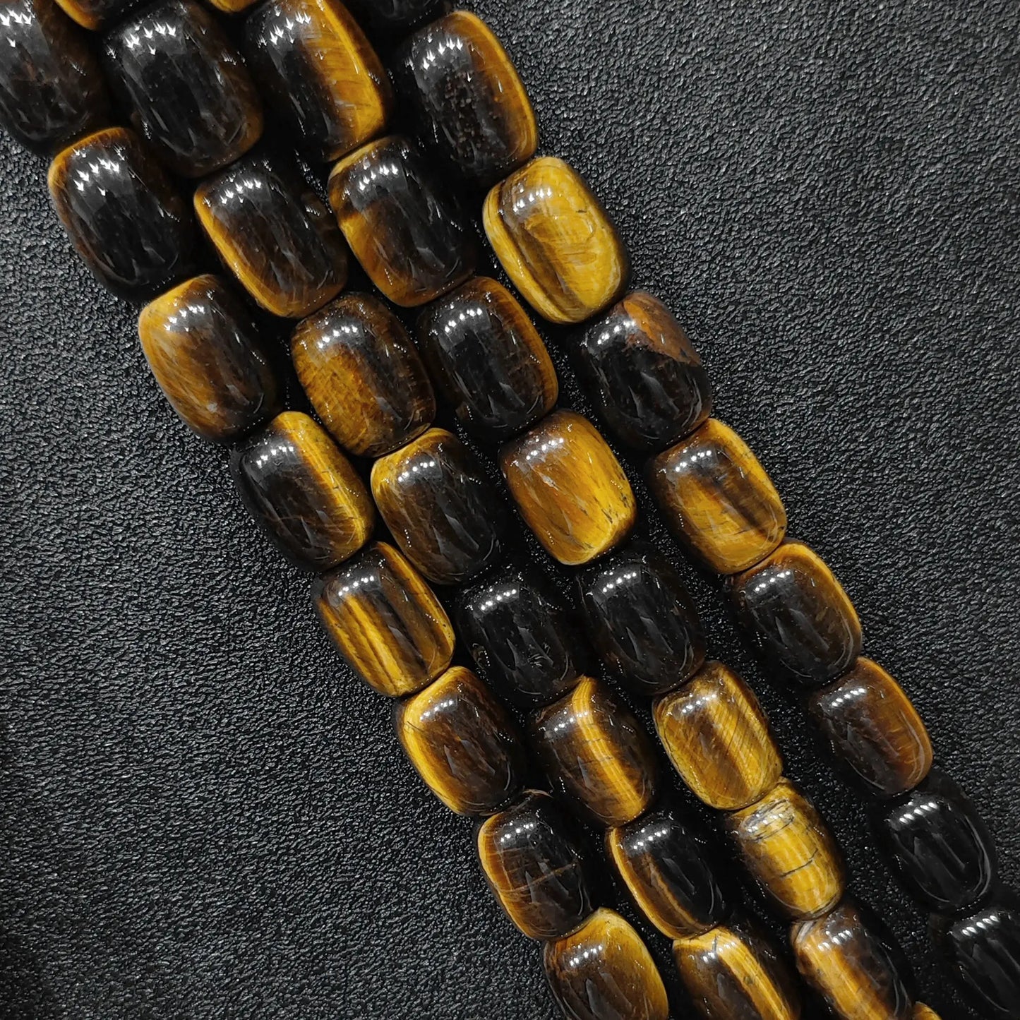 Macro closeup of natural yellow tigers eye barrel beads showing golden chatoyant bands