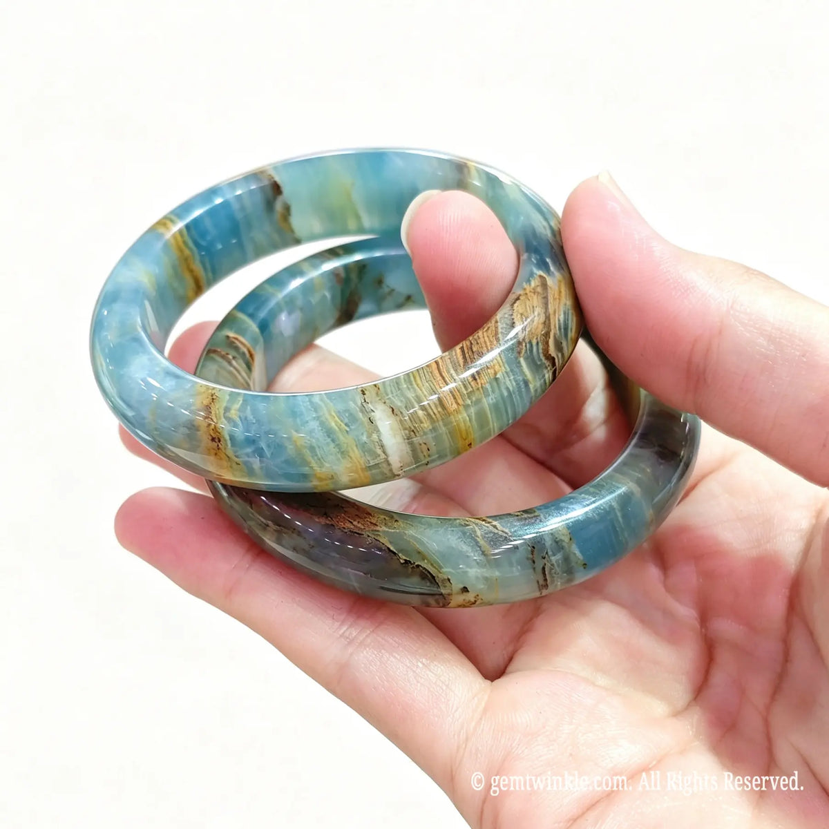 Two natural blue calcite bangles held together highlighting soft pastel blue and brown organic banding
