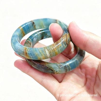 Two natural blue calcite bangles held together highlighting soft pastel blue and brown organic banding