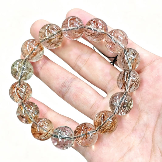 natural black gold super seven crystal bead bracelet held in hand showing metallic copper gold and black rutile inclusions
