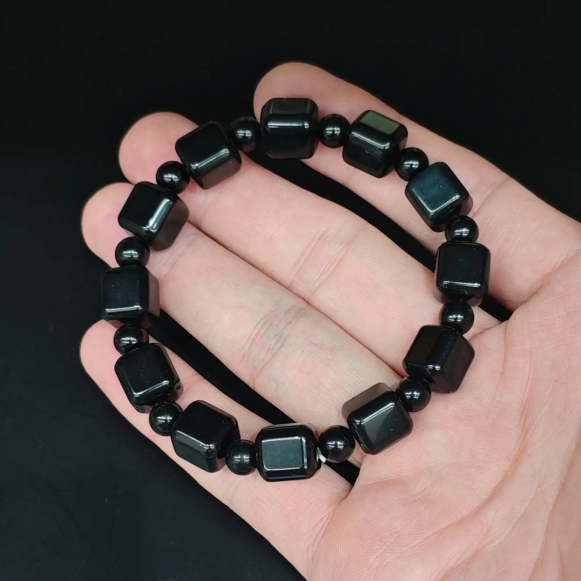 Natural black obsidian 10mm cube bead bracelet held close up showing smooth rounded edges and high gloss polish