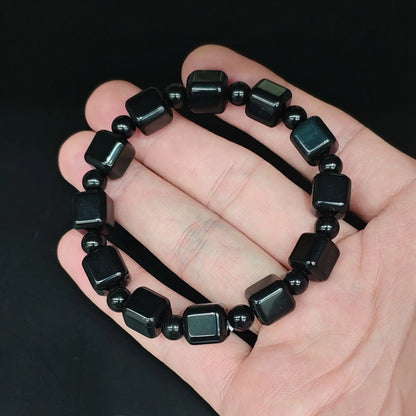 Natural black obsidian 10mm cube bead bracelet held close up showing smooth rounded edges and high gloss polish