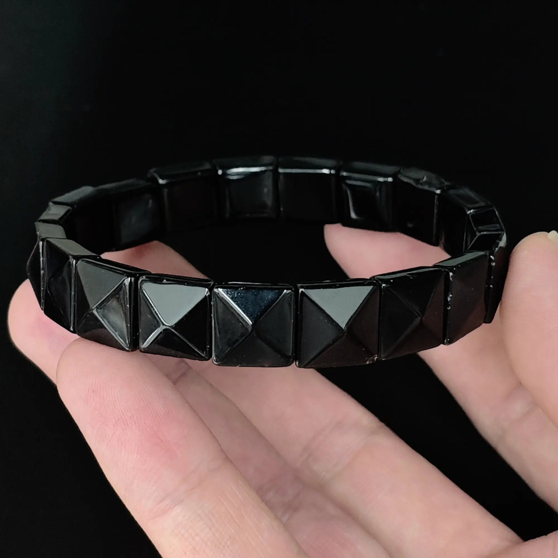 Natural black obsidian 11mm pyramid faceted square bead bracelet held in hand showing raised geometric pyramid tops