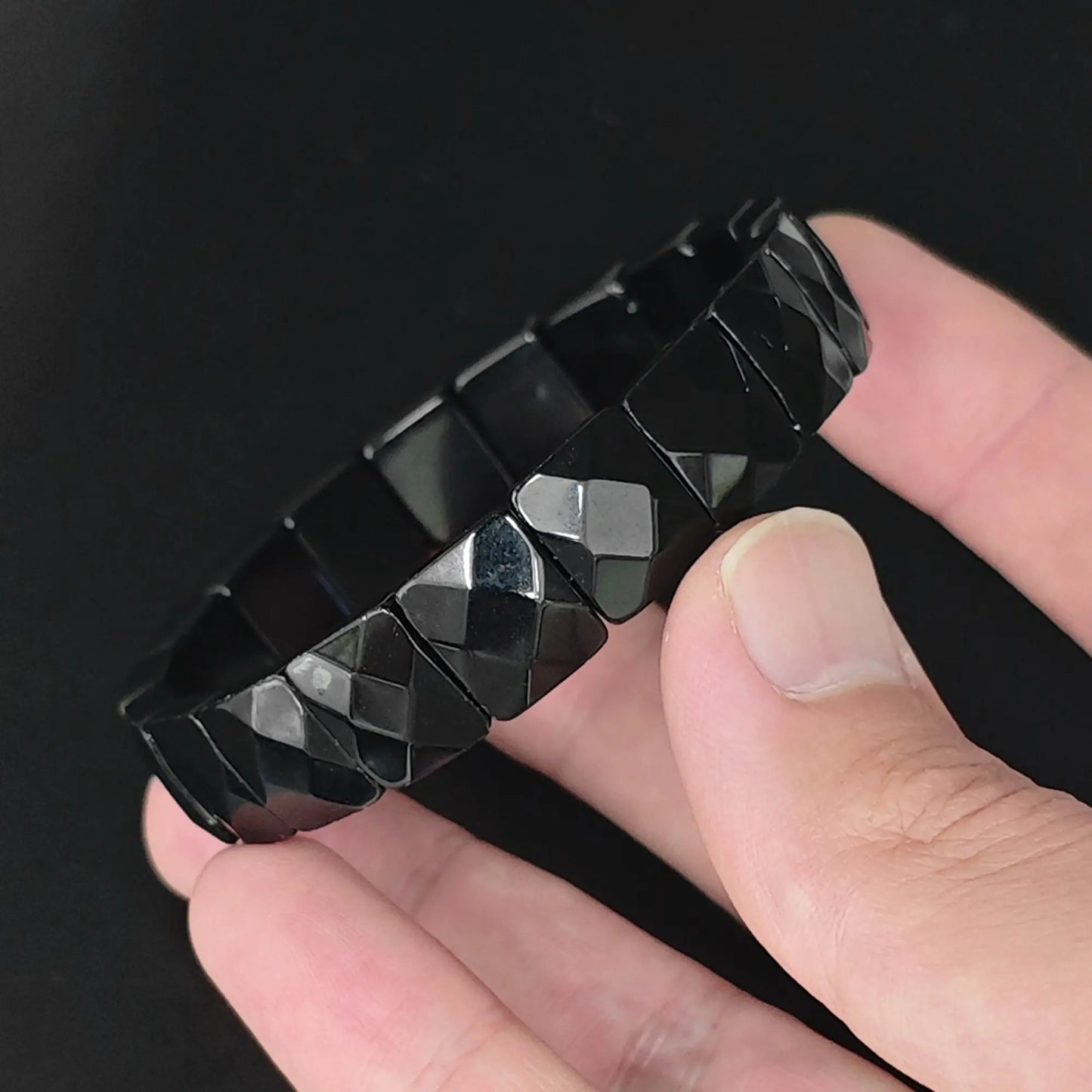 Natural black obsidian 12mm diamond faceted square bead bracelet held in hand showing geometric light reflections
