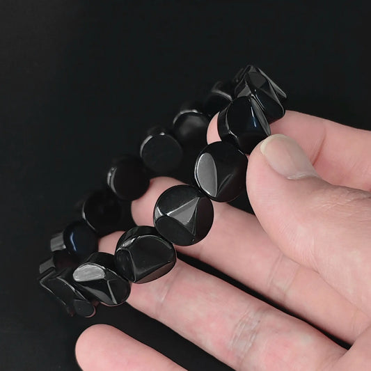 Natural black obsidian 12mm triangle faceted flat round disc bead bracelet held in hand showing raised central triangle facets