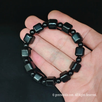 Natural black obsidian cube spacer bracelet top view resting open in hand showcasing glossy reflective glass surface