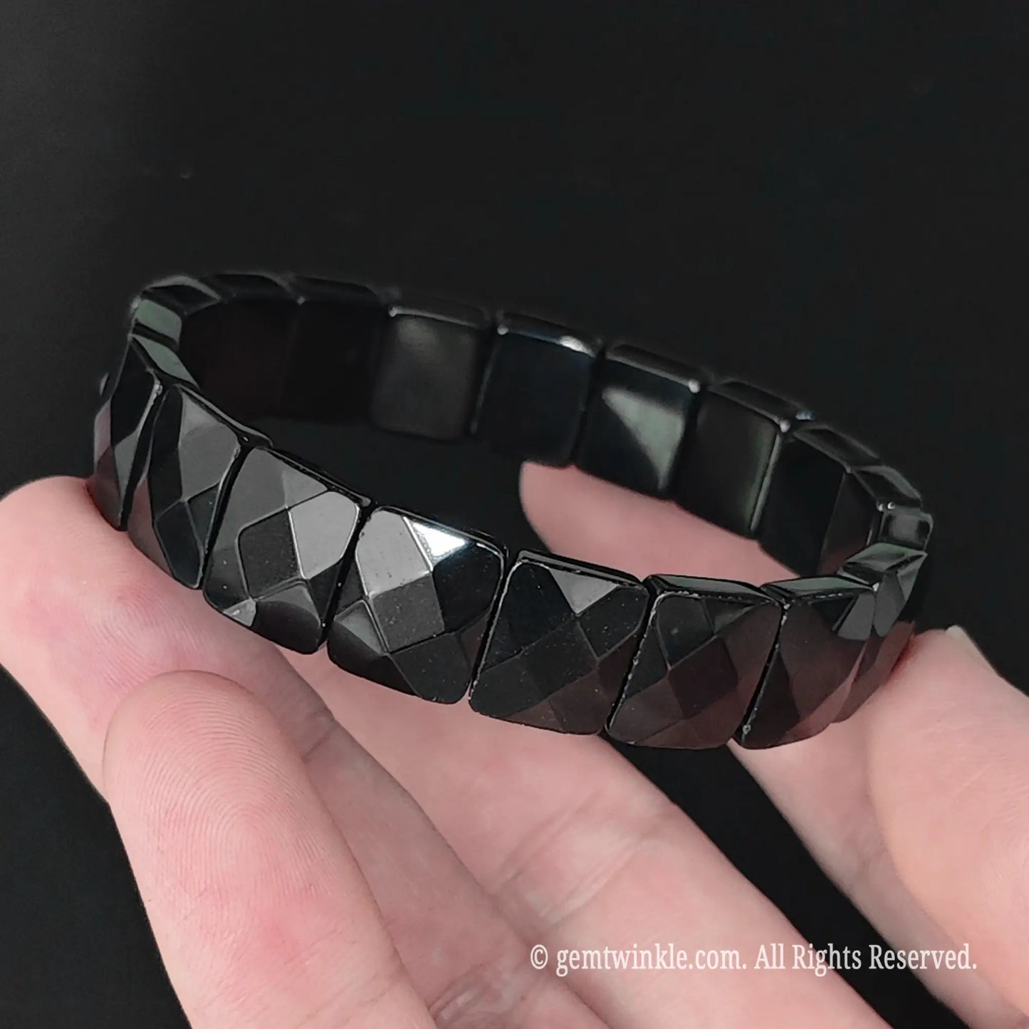 Full view of natural black obsidian geometric faceted bead bracelet resting in hand showcasing high polish finish