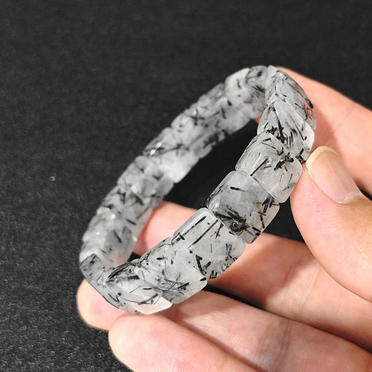 natural black tourmalinated quartz plate bracelet held in hand showing black tourmaline needles in clear quartz