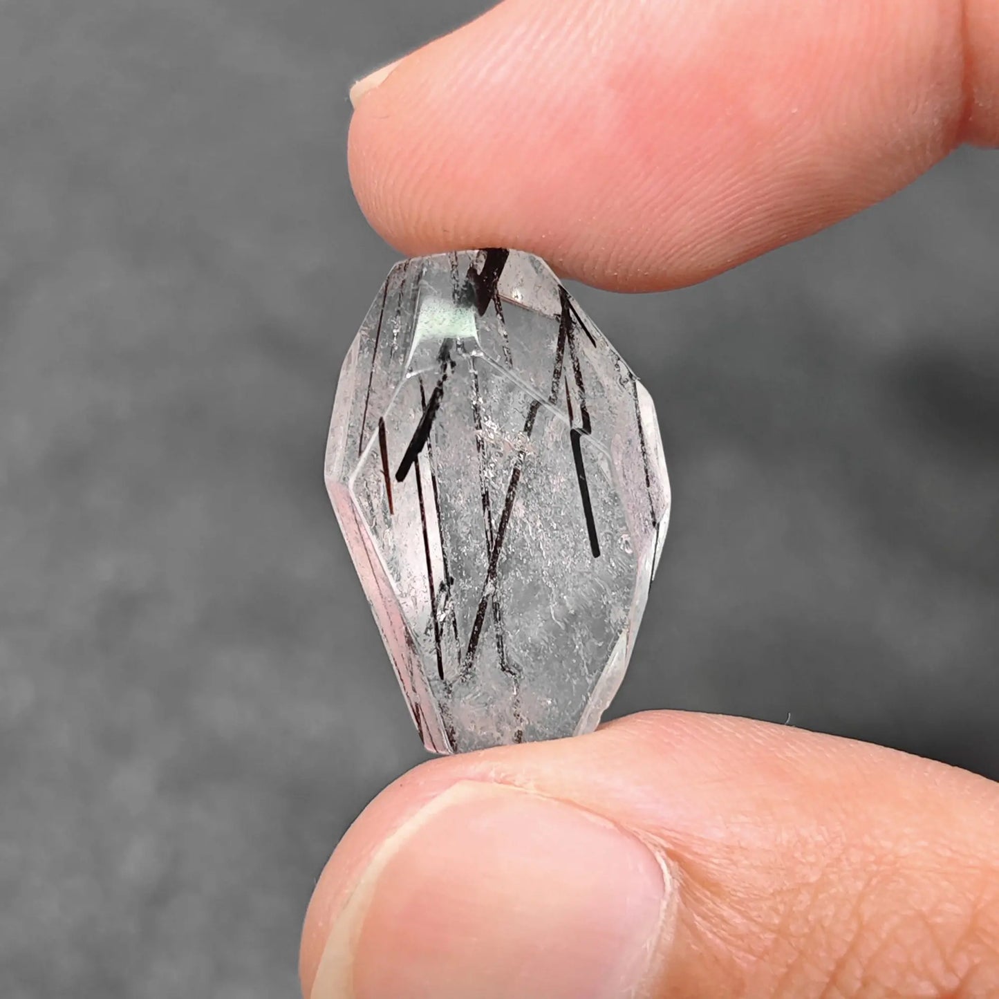 natural black tourmaline rutilated quartz 20mm freeform geometric bead held between fingers