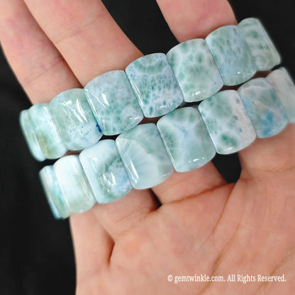 Pair of natural blue larimar stretch bracelets held in hand showing smooth polish and seafoam green tones