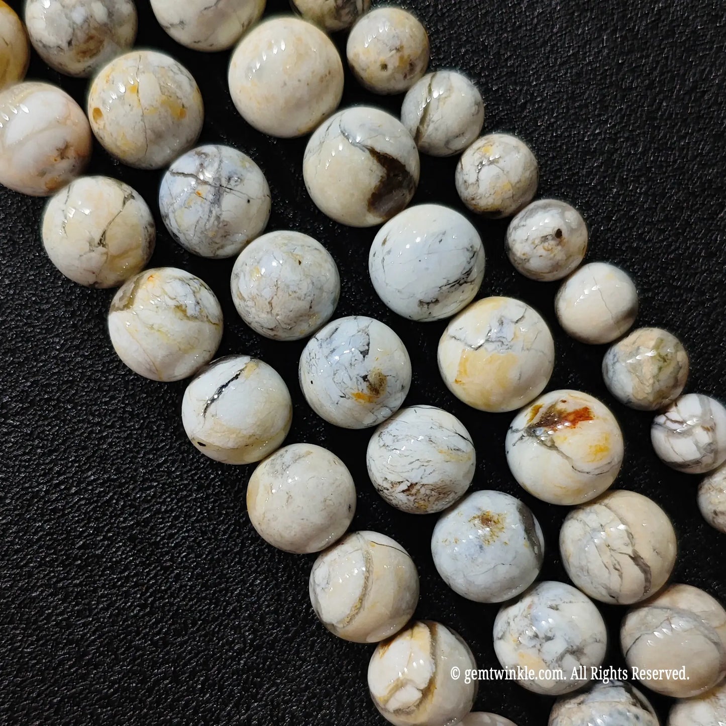 natural blue opal matrix loose bead strands from seven millimeter to twelve millimeter sizes arranged on black leather surface