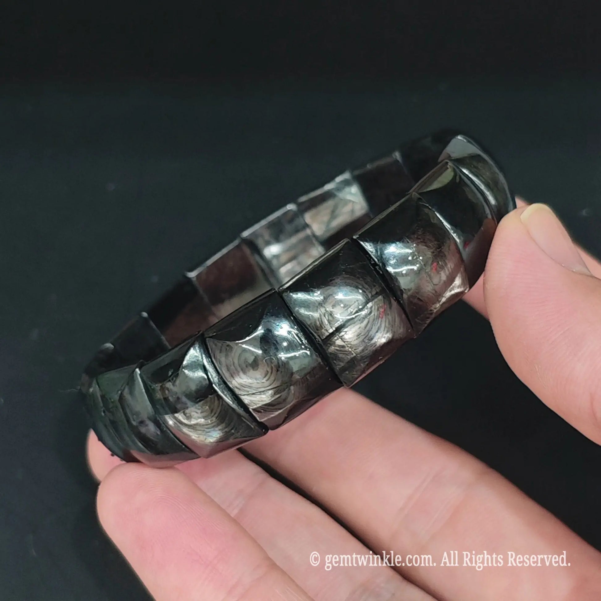 Full view of natural bronze sheen hypersthene bamboo tile bracelet resting open in hand showcasing metallic luster