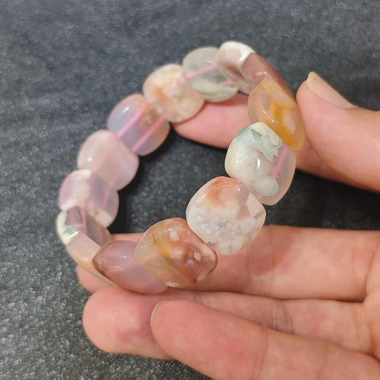 natural cherry blossom agate bracelet featuring 17x14mm cushion-cut square beads held in hand showing soft pink flower patterns