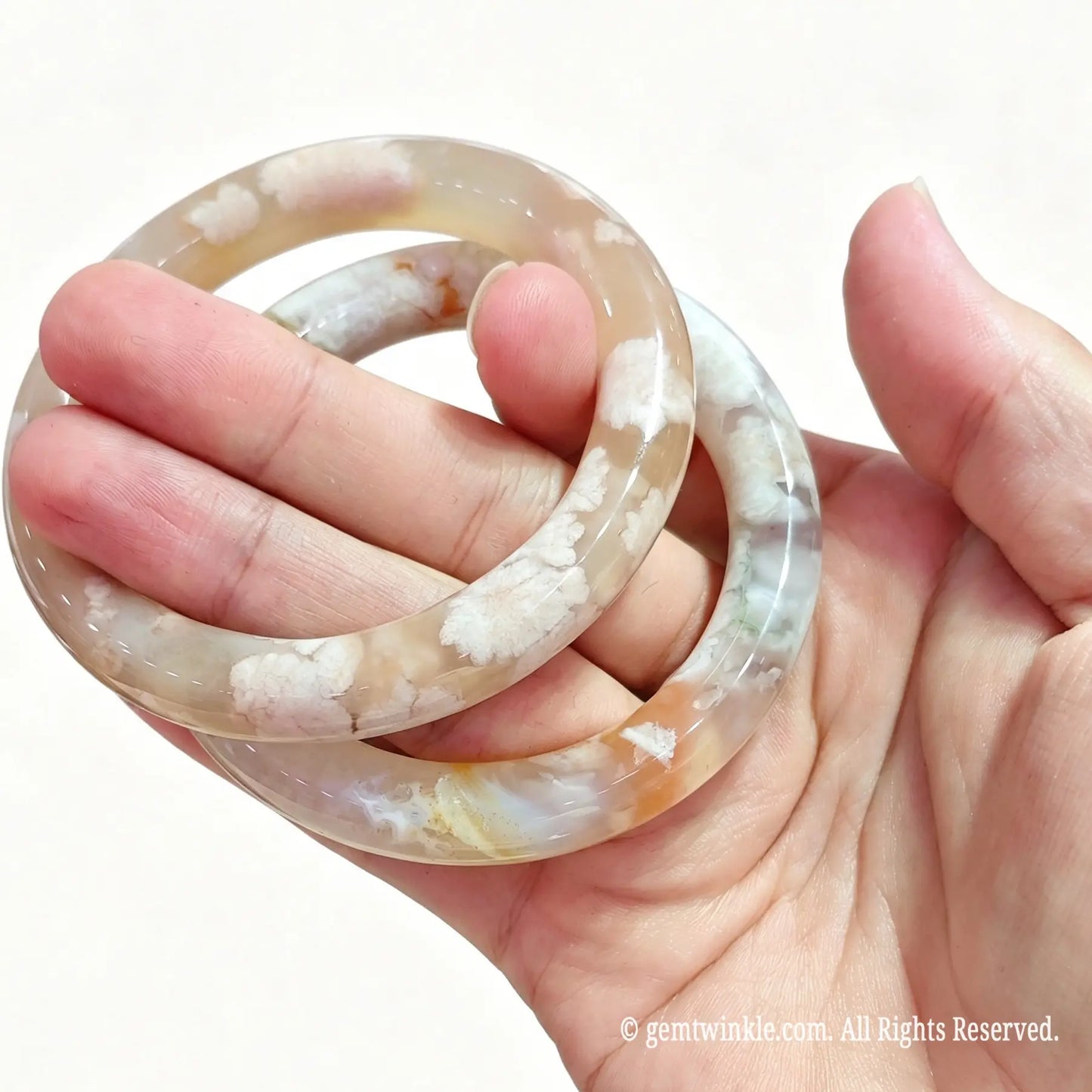 Two natural blossom agate bangles held together displaying 3D mineral floral plumes inside translucent matrix